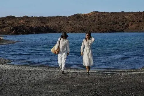 two women in white clothes walking on beach
