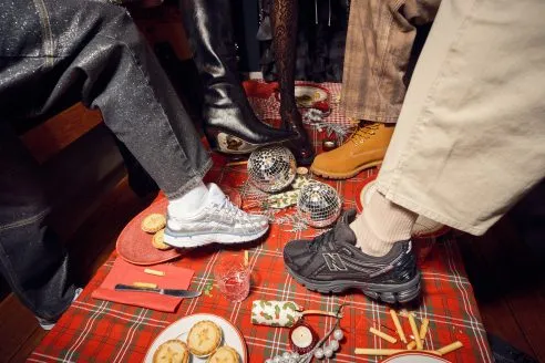 still from Schuh's Christmas 2025 ad featuring models showcasing trainers on table